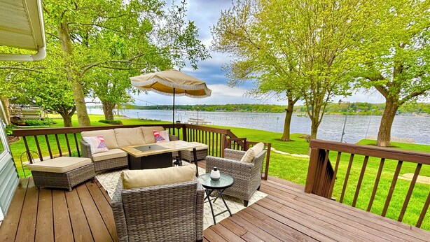 A wooden deck with wicker furniture, a small table, and an umbrella.