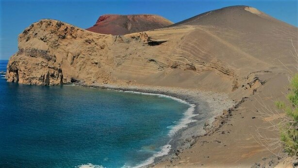 Un paysage côtier caractérisé par une falaise rocheuse imposante et une plage.