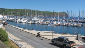 Un port de plaisance où sont amarrés de nombreux voiliers, une route asphaltée et un véhicule garé.