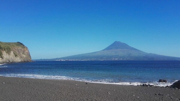 A beach with a mountain in the background. - Family House - great view Horta Bay (Horta)