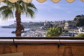 A coastal cityscape with a beach, buildings, and a palm tree. - Beachfront Studio with Terrace by Wonderful Italy (Genova)