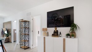 A modern interior with a white console table, a large abstract painting, a statue, and potted plants. - Holiday Home 'Casita Dana' with Private Pool, Wi-Fi and Air Conditioning (Conil de la Frontera)