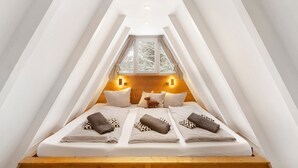 A triangular attic bedroom with a bed, pillows, and a small deer figurine.