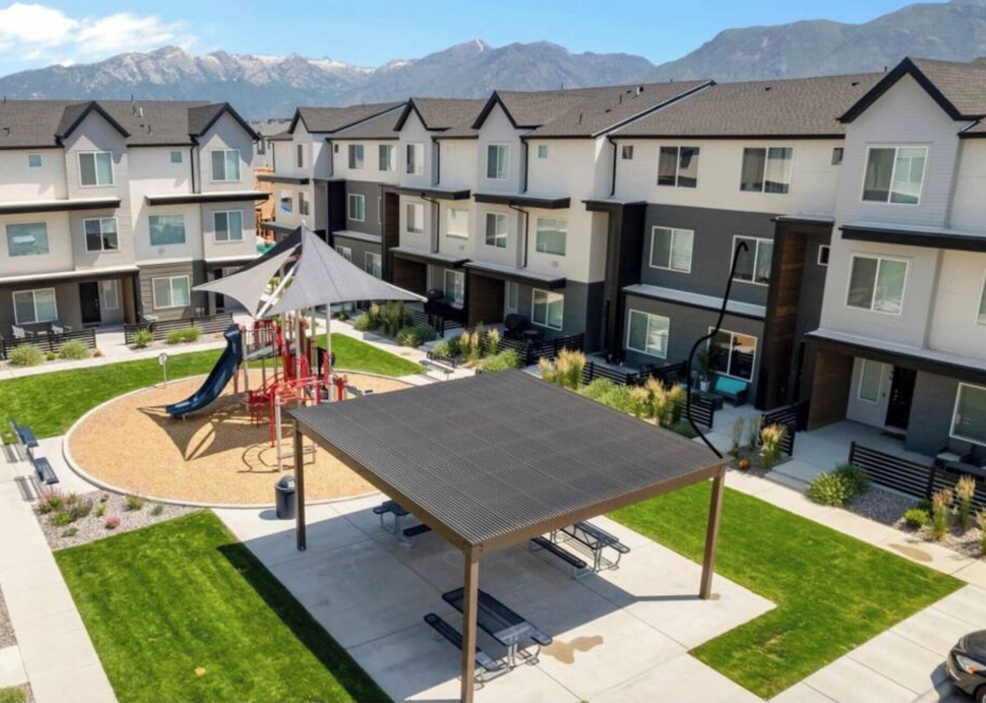 A residential complex with modern architecture, a playground, and a covered seating area.