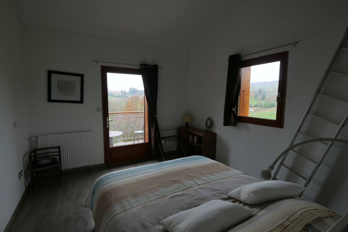 A bedroom with a bed, a radiator, a window, and a view of the outdoors.