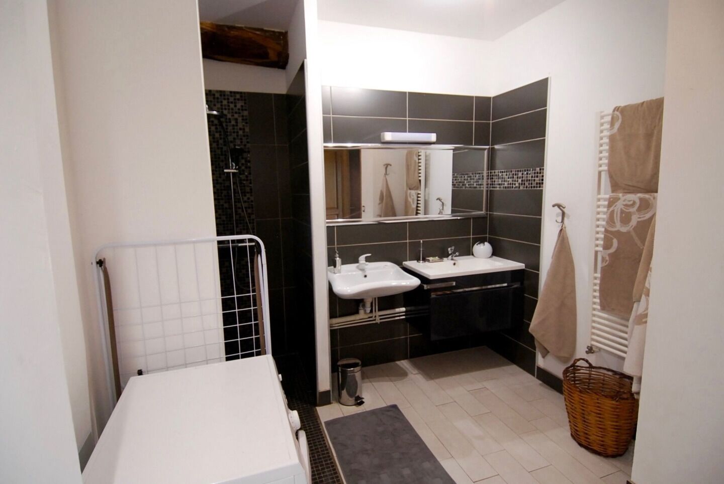 Ein Badezimmer mit Dusche, zwei Waschbecken, einem Handtuchhalter und einem Heizkörper.