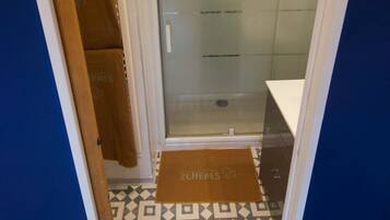 A narrow hallway leading to a glass-enclosed shower area with a patterned floor.