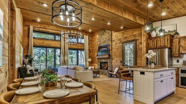 Un salón amplio con chimenea, techo de madera y ventanas grandes.