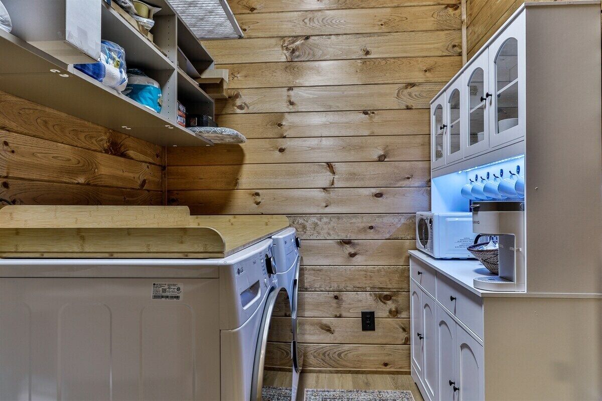 Una cucina compatta con pareti in legno, una lavatrice, un forno a microonde e un piccolo frigorifero.