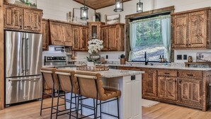 Una cocina con armarios de madera, electrodomésticos de acero inoxidable, un ventanal grande y una barra.