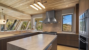 Una cocina moderna con una isla grande, electrodomésticos de acero inoxidable y vistas al exterior.