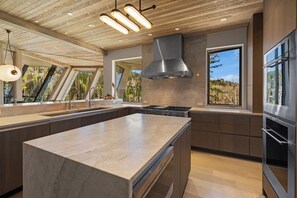 A modern kitchen with a large island, stainless steel appliances, and a view of the outdoors. - Monteluce by Exceptional Stays (MOUNTAIN VILLAGE)