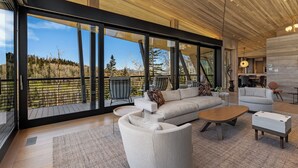 A spacious living area with a large window overlooking a forested landscape.
