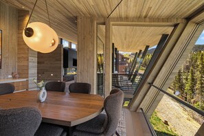 A modern interior with a wooden dining table, chairs, and a hanging light fixture.