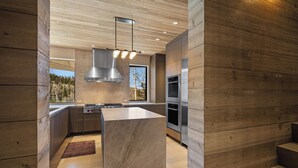 A modern kitchen with a central island, stainless steel appliances, and wooden paneling.