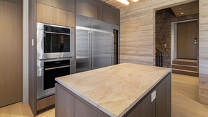 Una cocina moderna con electrodomésticos de acero inoxidable, armarios de madera y encimera de mármol.