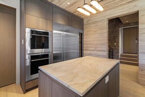 A modern kitchen with stainless steel appliances, wooden cabinetry, and a marble countertop. - Monteluce by Exceptional Stays (MOUNTAIN VILLAGE)