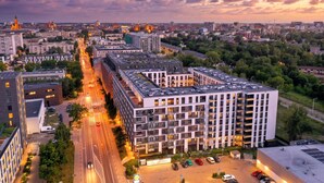A multi-story building with a parking lot, surrounded by trees and other buildings. - RentPlanet - Apartament Braniborska IV (Wrocław)