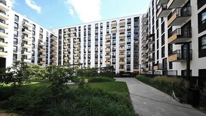 A multi-story residential building with balconies, a paved walkway, and a landscaped garden area. - RentPlanet - Apartament Braniborska IV (Wrocław)