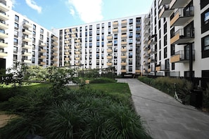A multi-story residential building with balconies, a paved walkway, and a landscaped garden area. - RentPlanet - Apartament Braniborska IV (Wrocław)