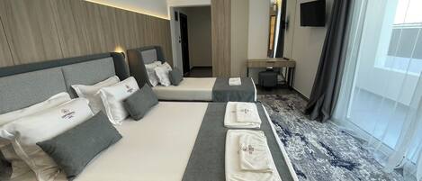 Une chambre d’hôtel avec deux lits, un bureau, un miroir et une grande fenêtre.