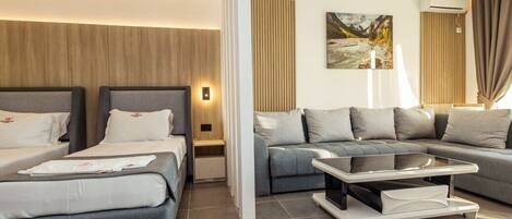 Una habitación de hotel moderna con dos camas, un sofá, una mesa de centro y un ventanal con cortinas.