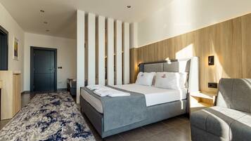 Una habitación de hotel moderna con una cama grande, un sofá gris, un tapete estampado y una pared de acento de madera.