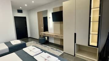 A modern hotel room with two beds, a flat-screen TV, a wardrobe, and a built-in shelf.