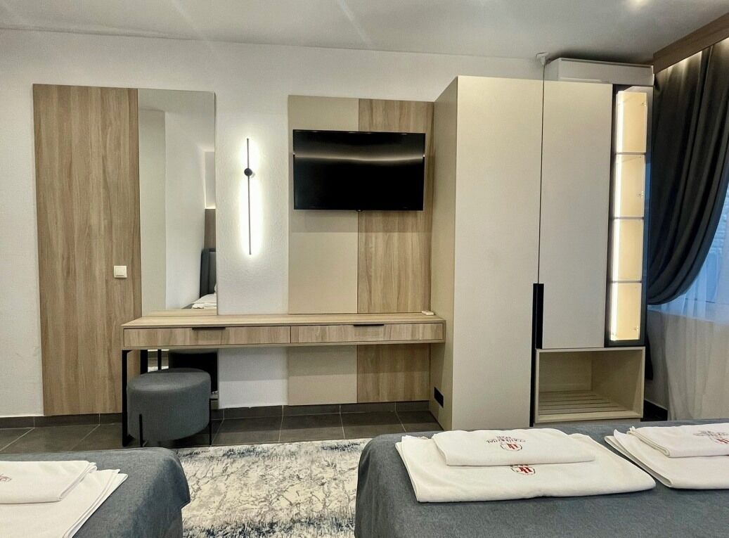 Una habitación de hotel moderna con una cama grande, un escritorio, un televisor de pantalla plana y un armario.