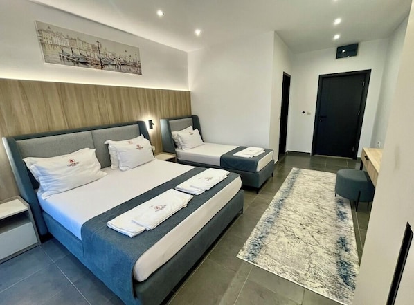 Une chambre d’hôtel moderne avec deux lits, une grande moquette et un tableau représentant un paysage urbain accroché au mur.