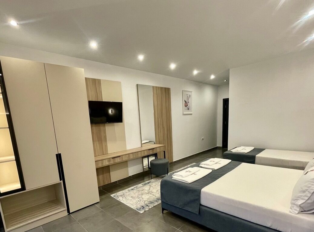 Une chambre d’hôtel moderne équipée d’un lit, de tables de chevet, d’une télévision et d’un bureau.