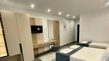 Une chambre d’hôtel moderne équipée d’un lit, de tables de chevet, d’une télévision et d’un bureau.