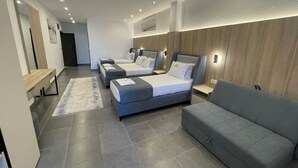 A modern hotel room with three beds, a sofa, and a large mirror. - Hotel Continental Ulcinj (Ulcinj)