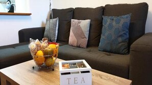 A living room with a dark brown sofa, a wooden coffee table, a basket of fruits, and a white box labeled "TEA". - Cozy townhouse in Vera, just steps from the beach (vera)