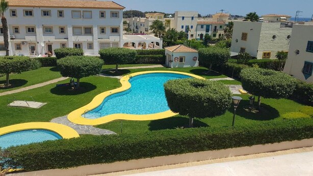A residential area with a large swimming pool surrounded by well-maintained lawns and hedges. - Cozy townhouse in Vera, just steps from the beach (vera)