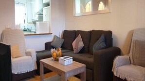 A living room with a sofa, armchairs, a coffee table with a box labeled "TEA", and a kitchen in the background. - Cozy townhouse in Vera, just steps from the beach (vera)
