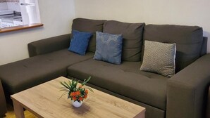 A modern living room with a sectional sofa, a wooden coffee table, and a kitchen area with a refrigerator and microwave. - Cozy townhouse in Vera, just steps from the beach (vera)