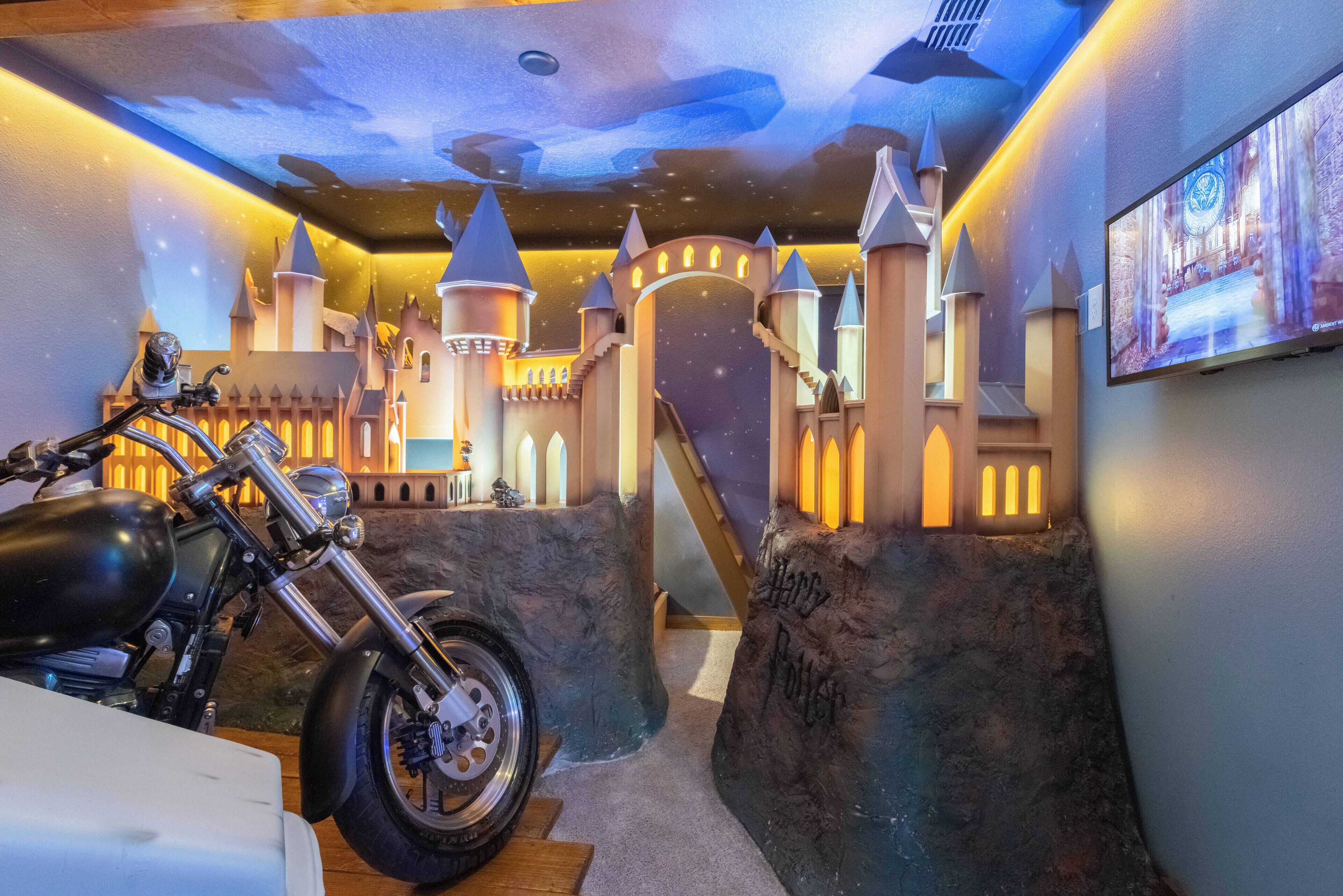 A room with a motorcycle, a castle-themed mural, and a Harry Potter-themed wall.