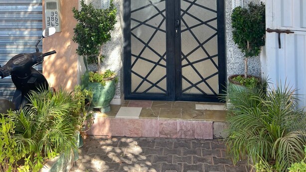 A building entrance with a large black gate, potted plants, and a motorbike parked outside. - Modern apartment in the heart of Marrakech, 9 min from airport -with Wi-Fi & A/C (Marrakech)