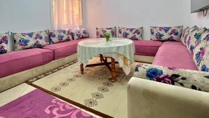 A living room with a sofa set, a round coffee table, a chandelier, and a patterned rug. - Modern apartment in the heart of Marrakech, 9 min from airport -with Wi-Fi & A/C (Marrakech)