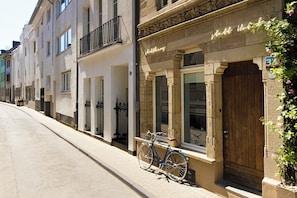 A row of buildings with a bicycle parked in front of a building with a wooden door and a neon sign.
