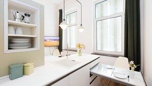 Eine moderne Küche mit weißen Schränken, einer eingebauten Spüle und einem Essbereich mit Tisch für zwei Personen.