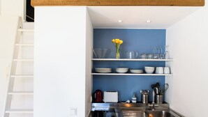 A kitchen with white shelves, a sink, and a coffee maker. - Sunny, quiet city apartment with sleeping gallery and small private courtyard (Köln)
