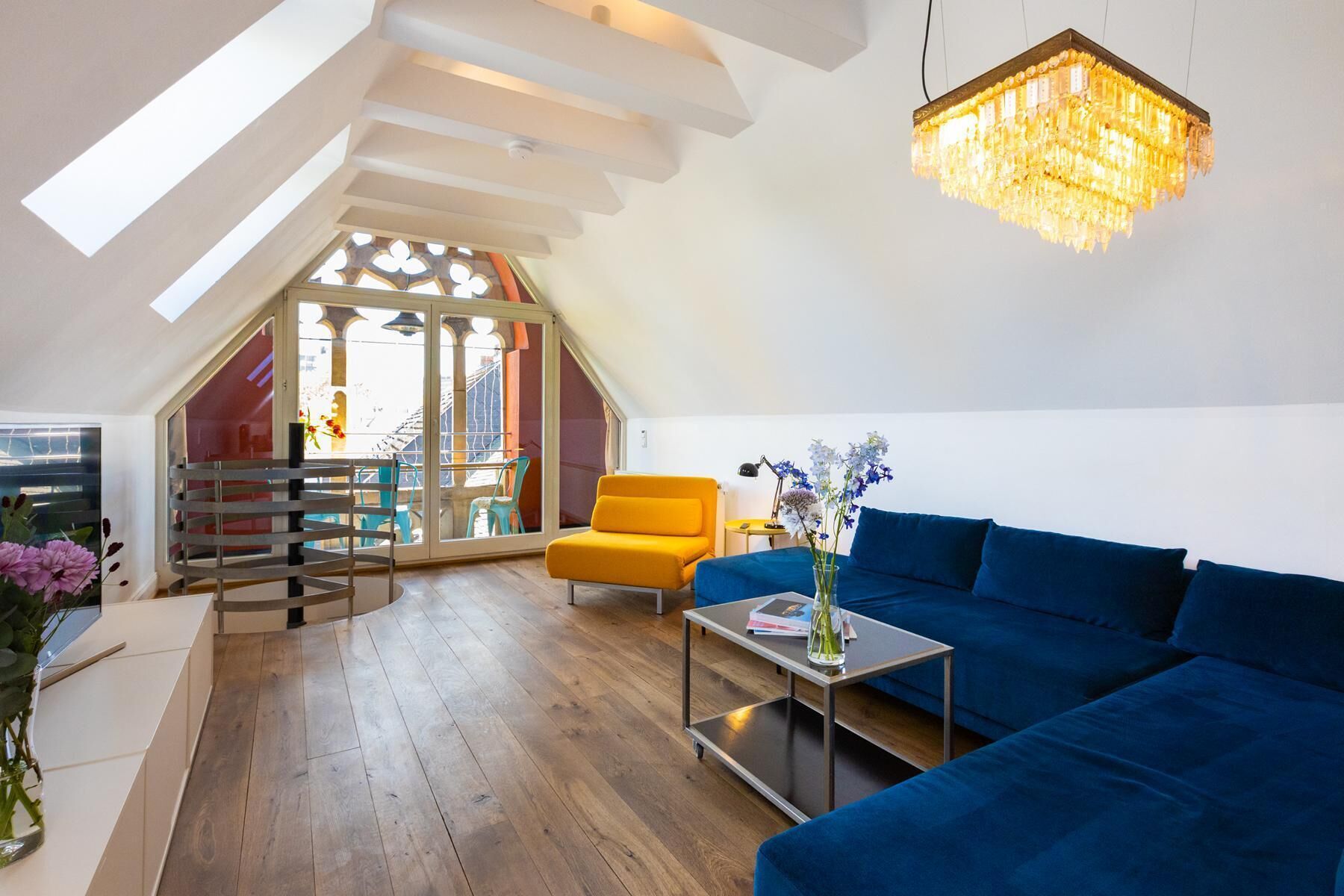 A spacious loft with a blue sofa, a small table, and a chandelier.