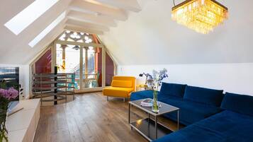A spacious loft with a blue sofa, a small table, and a chandelier.