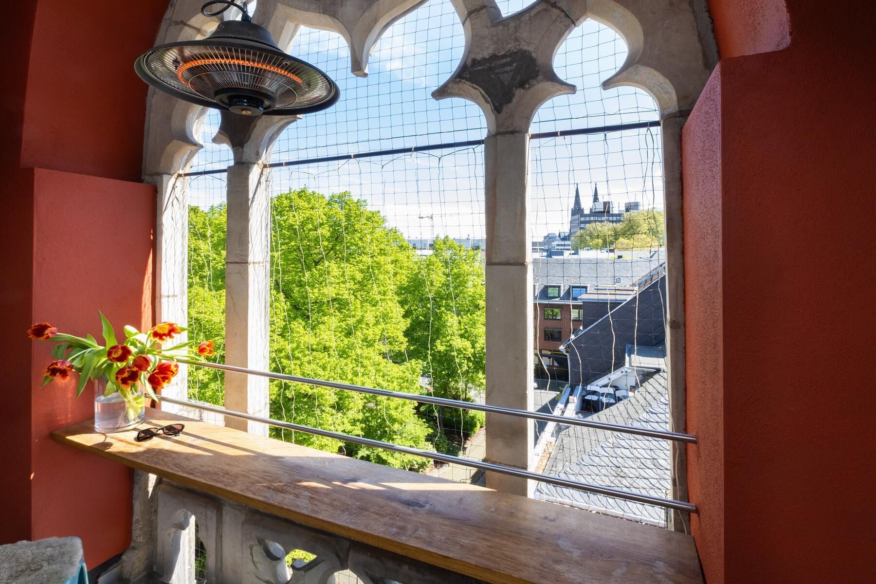 A window with a view of a cityscape, a heater, and a vase with flowers.