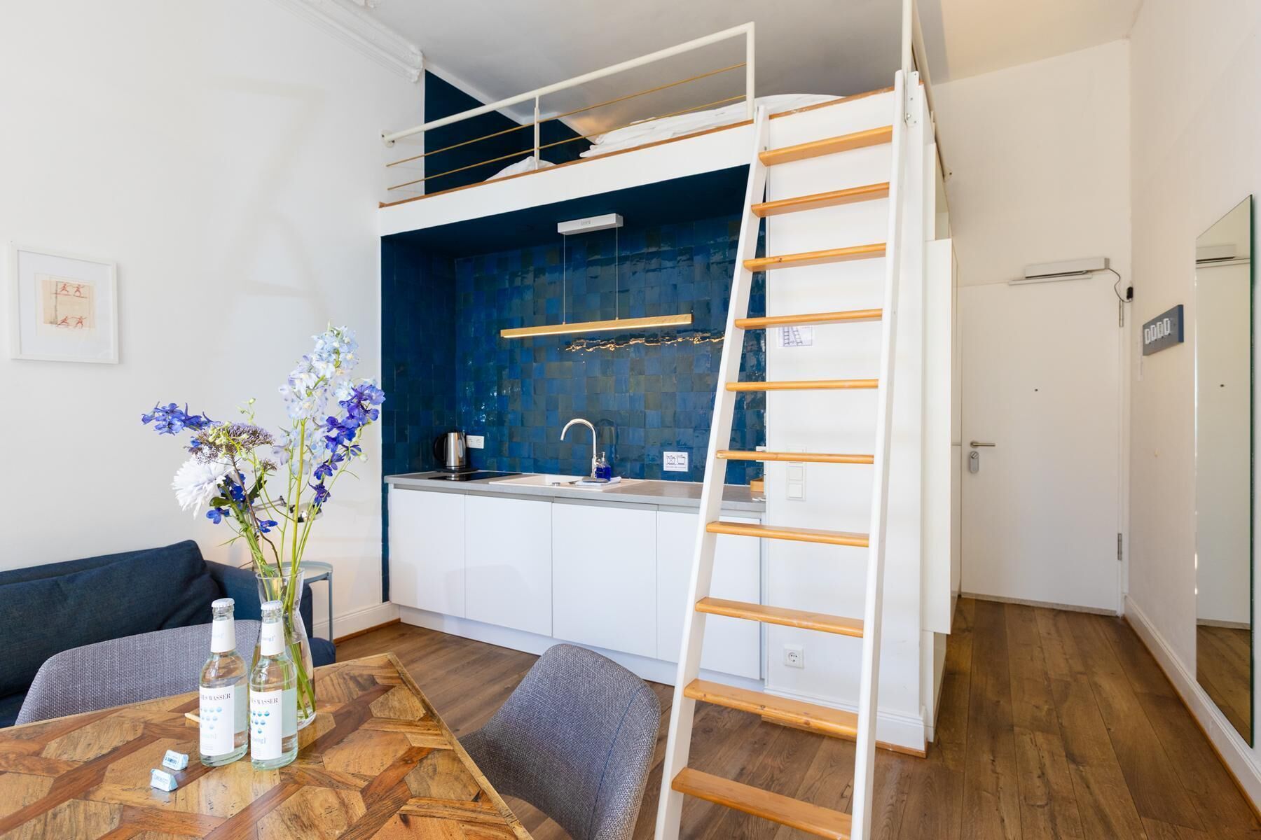 A compact kitchen with a built-in stove, a sink, and a blue backsplash.