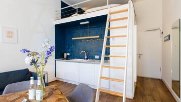A compact kitchen with a built-in stove, a sink, and a blue backsplash.