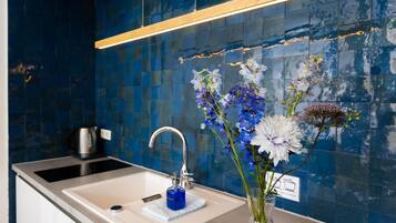A bathroom with a sink, a mirror, and a blue tiled wall.