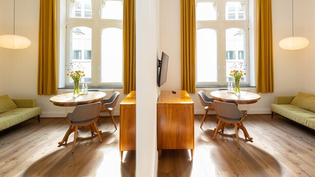 A room with two round tables, a sofa, and a TV.